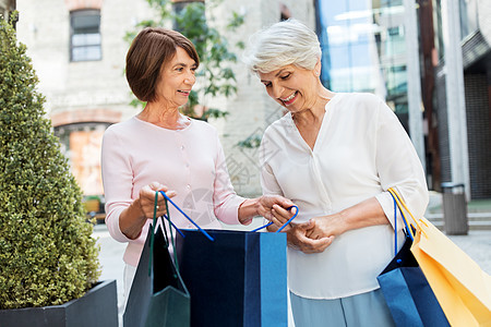 销售,消费主义人的两个老年女子朋友带着购物袋塔林市街城里购物袋的高级女人图片