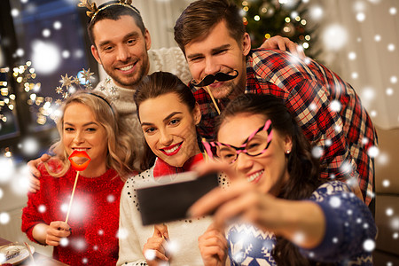 节日庆祝快乐的朋友与派道具自拍智能手机家里诞晚餐雪朋友们诞晚餐上自拍背景图片