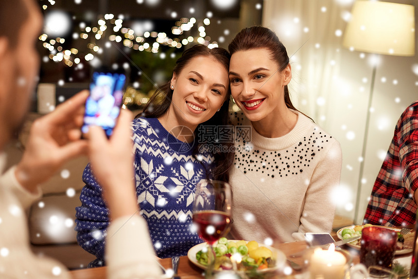 节日庆祝快乐的朋友家里吃诞晚餐,用智能手机雪地上拍照朋友们吃诞晚餐拍照图片