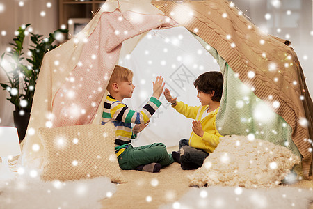 童诞节友谊的快乐的男孩孩子们的帐篷雪上的帐篷里玩拍手游戏男孩孩子们的帐篷里玩拍手游戏图片