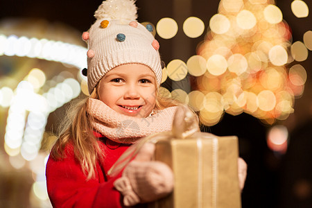 冬季晚上诞市场上带礼物的快乐女孩图片