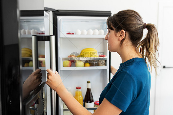 女人打开厨房里的冰箱图片
