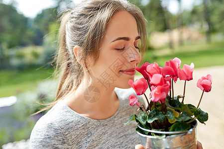 农业,园艺人们的快乐的轻女人闻着粉红色的仙客来花盆栽夏天的花园夏天花园里仙客来花的轻女人图片