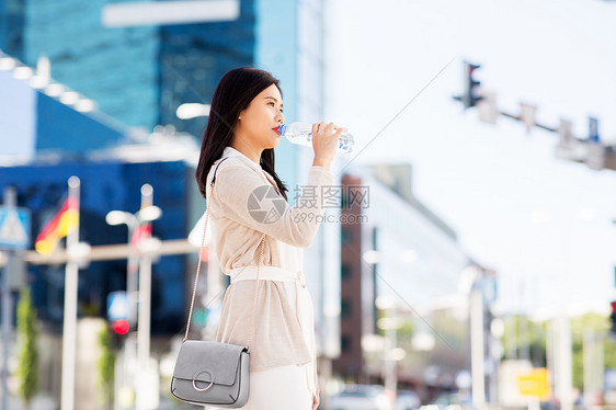 生活方式人们的轻的亚洲妇女饮用水粉塑料瓶城市亚洲女人城市的瓶子里喝水图片