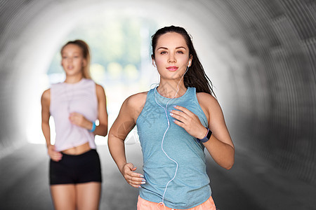 健身,运动健康的生活方式轻的妇女女朋友与耳机运行户外耳机运行的女女朋友图片