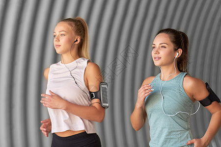 健身运动健康的生活方式轻女女朋友戴着带智能手机的,户外跑步带着耳机智能手机的轻女跑步图片