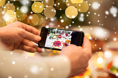 食物技术假日雪上的诞晚餐上,用智能手机拍摄蛋糕诞节晚餐时双手拍照食物图片