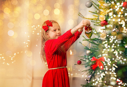 诞节,假日童的快乐的女孩穿着红色的衣服装饰自然冷杉树穿着红色连衣裙装饰诞树的快乐女孩图片