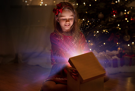 诞节,假期童的快乐的小女孩打开礼品盒与魔法灯黑暗中家里微笑的女孩晚上打开诞礼物图片