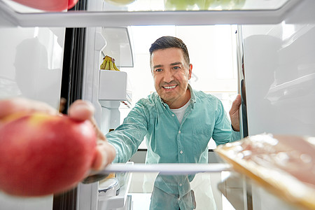 健康的饮食,食物饮食快乐的中男子冰箱家里厨房苹果男人家里厨房的冰箱里苹果图片