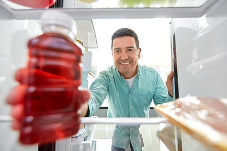 健康的饮食,食物饮食中男子冰箱家里厨房瓶果汁男人家里厨房的冰箱里果汁图片