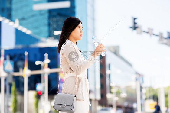 生活方式人们的轻的亚洲妇女饮用水粉塑料瓶城市亚洲女人城市的瓶子里喝水图片