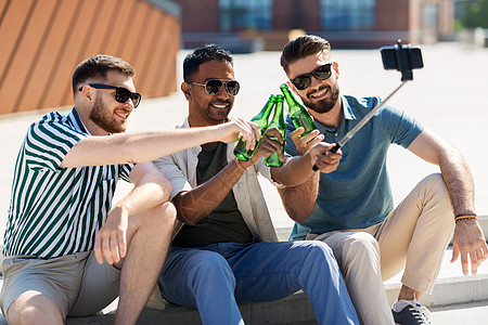 休闲技术人的快乐的男朋友自拍杆上用智能手机拍照,夏天街上品尝啤酒男人品尝啤酒,用智能手机自拍图片