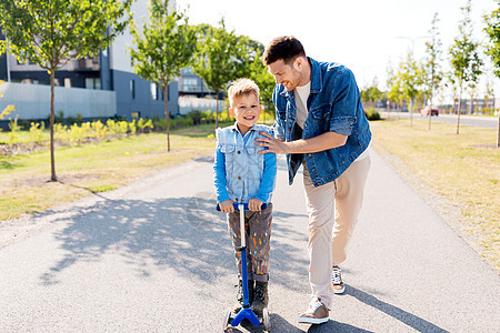 家庭,休闲父亲的快乐的父亲花时间小儿子骑滑板车城市快乐的父亲小儿子城市骑滑板车图片