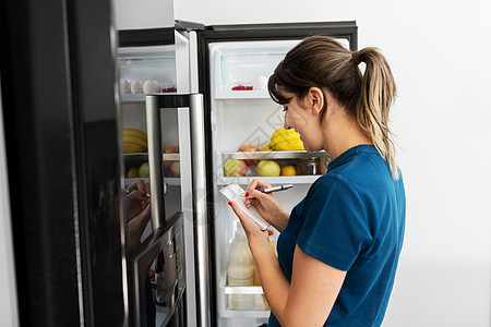 健康的饮食饮食妇女打开冰箱列出必要的食物家庭厨房女人家里冰箱里列出必要的食物清单图片
