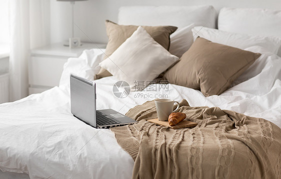舒适,内部笔记本电脑,杯咖啡牛角包床上舒适的家笔记本电脑,杯咖啡牛角包家里的床上图片