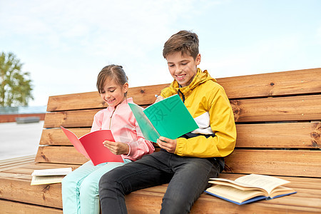 教育,童人的快乐的学校孩子兄弟姐妹,笔记本书坐木制的街道长凳上户外学校的孩子们着笔记本坐长凳上图片