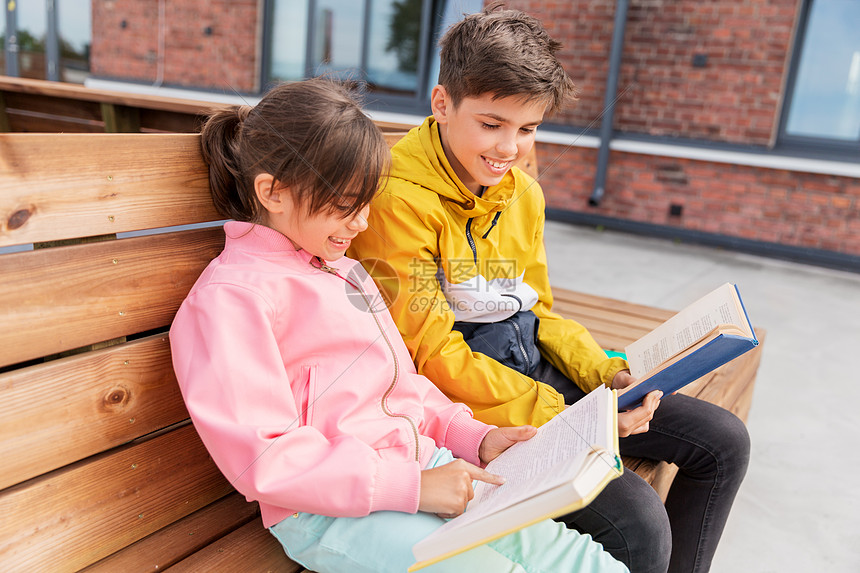 教育童人的快乐的学校孩子兄妹阅读书籍坐木制的街道