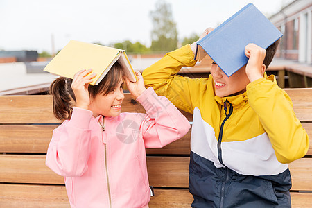 教育,童人的快乐的学校孩子兄弟姐妹,书坐木制的街道长凳上户外,玩得开心学校的孩子带着书户外玩图片