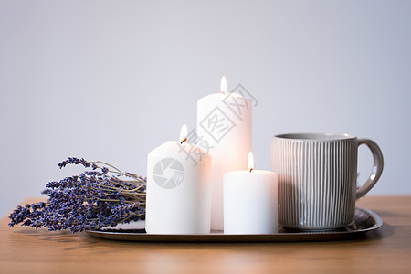 装饰,舒适的燃烧的白色蜡烛,茶杯子薰衣草花盘桌子上蜡烛,杯子里的茶桌子上的薰衣草花图片