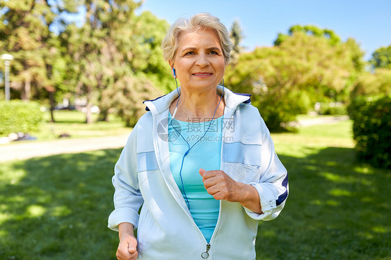 健身,运动健康的生活方式老妇女与耳机听音乐跑步夏季公园戴着耳机夏天公园跑步的高级女人图片
