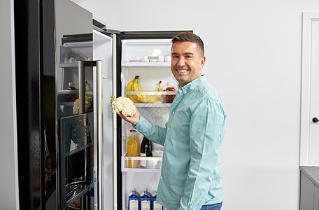 健康饮食,食物蔬菜饮食快乐的中男子冰箱里花椰菜家厨房男人家里厨房的冰箱里蔬菜图片
