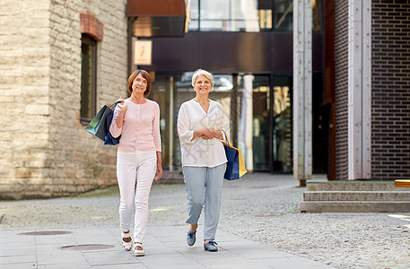 销售,消费主义人的两个老年女子朋友带着购物袋走塔林市街带着购物袋城里散步的老年女子图片