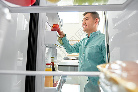 健康的饮食,食物饮食中男子冰箱家里厨房瓶果汁男人家里厨房的冰箱里果汁图片