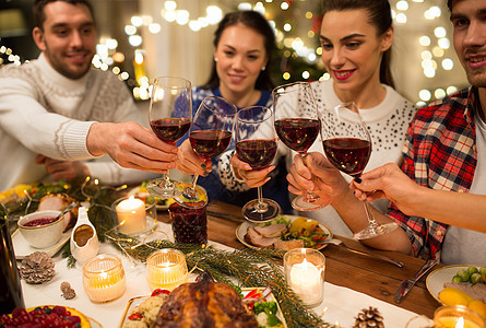 节日庆祝亲密的快乐朋友家里吃诞晚餐,喝红酒碰杯亲密的朋友用葡萄酒庆祝诞节图片