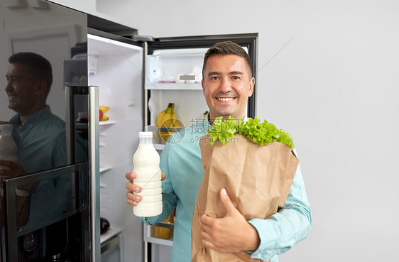 家里冰箱里新买的食物的男人图片