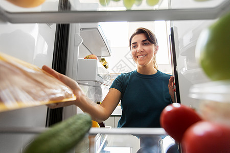 快乐的女人家里冰箱里的食物图片