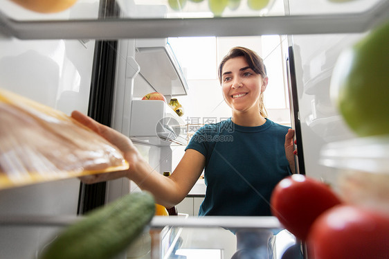 快乐的女人家里冰箱里的食物图片