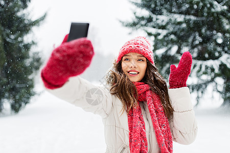冬天里轻的女人用智能手机自拍图片