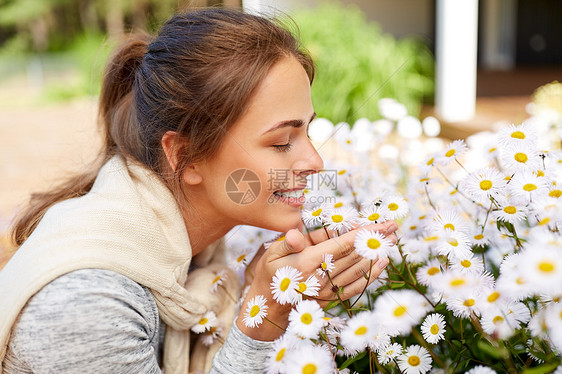 快乐的女人闻着花园里的洋甘菊花图片