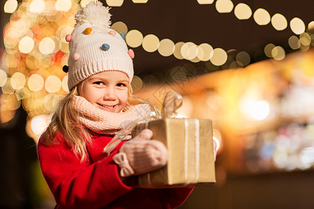 冬季晚上诞市场上带礼品盒的快乐女孩图片