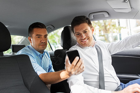 运输,车辆技术中男乘客后座他的智能手机给汽车司机男乘客向汽车司机展示智能手机图片