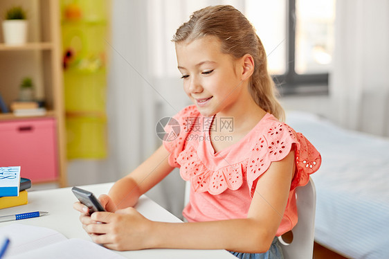 儿童,教育技术快乐的学生女孩家里用智能手机快乐的学生女孩家用智能手机图片