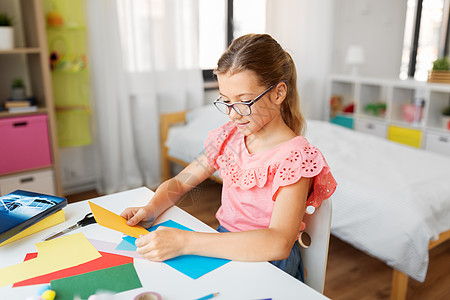 童,创造力爱好创意女孩戴着彩色纸坐家里的桌子上带着彩色纸的女孩坐家里的桌子上图片