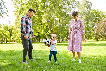 家庭,休闲人的快乐的母亲,父亲小儿子夏天的公园踢足球快乐的家庭夏天的公园踢足球图片