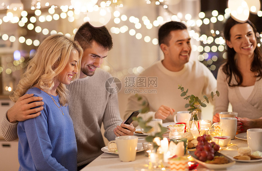 庆祝,假日人们的快乐的朋友家人与智能手机家里举行茶话会家茶话会上智能手机的快乐朋友图片