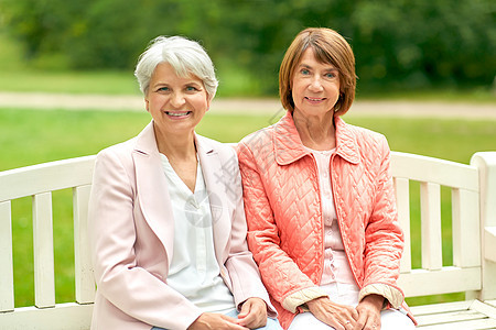 老退休人的两个老年女子朋友坐夏季公园的长凳上老年女子朋友坐公园的长凳上图片