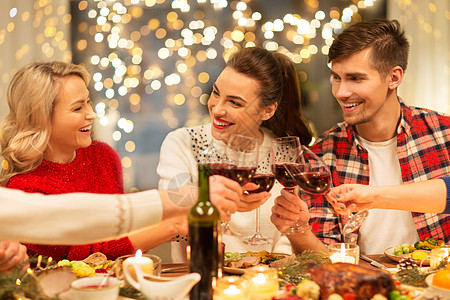 家庭晚餐节日庆祝快乐的朋友家里吃诞晚餐,喝红酒碰杯快乐的朋友诞节聚会上喝红酒背景