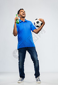 运动,休闲游戏成功快乐的印度男子足球迷与足球啤酒瓶庆祝胜利的灰色背景足球迷用足球庆祝胜利图片