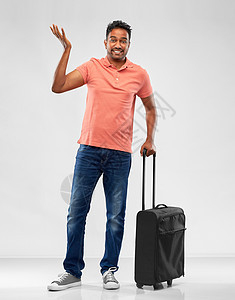 家庭,旅游度假困惑的印度男子穿着马球衫,旅行袋耸耸灰色背景上穿着马球衫的印度男人着旅行袋耸耸肩图片