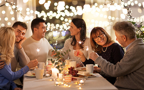 庆祝,节日诞节的快乐的家庭与火花家里的晚餐聚会上玩得很开心家里闪闪发光的人家里举行晚宴图片