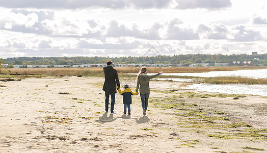 家庭休闲人的快乐的母亲父亲小儿子沿着秋天的海滩散步幸福的家庭沿着秋天的海滩散步图片