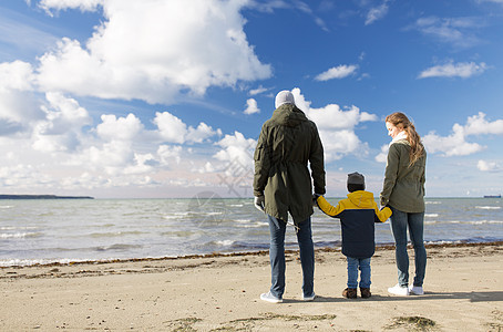 家庭休闲人的快乐的母亲,父亲小儿子秋天的海滩上看着大海快乐的家人秋天的海滩上看着大海图片