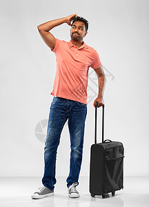 家庭,旅游度假困惑的印度男子穿着马球衫,旅行袋灰色背景困惑的印度男人着旅行袋耸耸肩图片