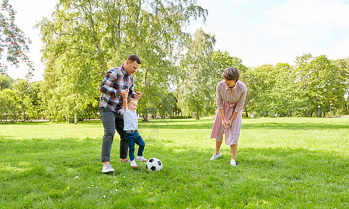 家庭,休闲人的快乐的母亲,父亲小儿子夏天的公园踢足球快乐的家庭夏天的公园踢足球图片