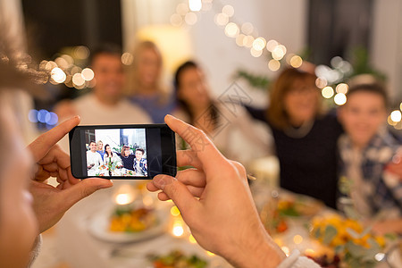 庆祝,假日人的男人与智能手机拍照家庭晚餐聚会晚宴上给家人拍照的男人图片